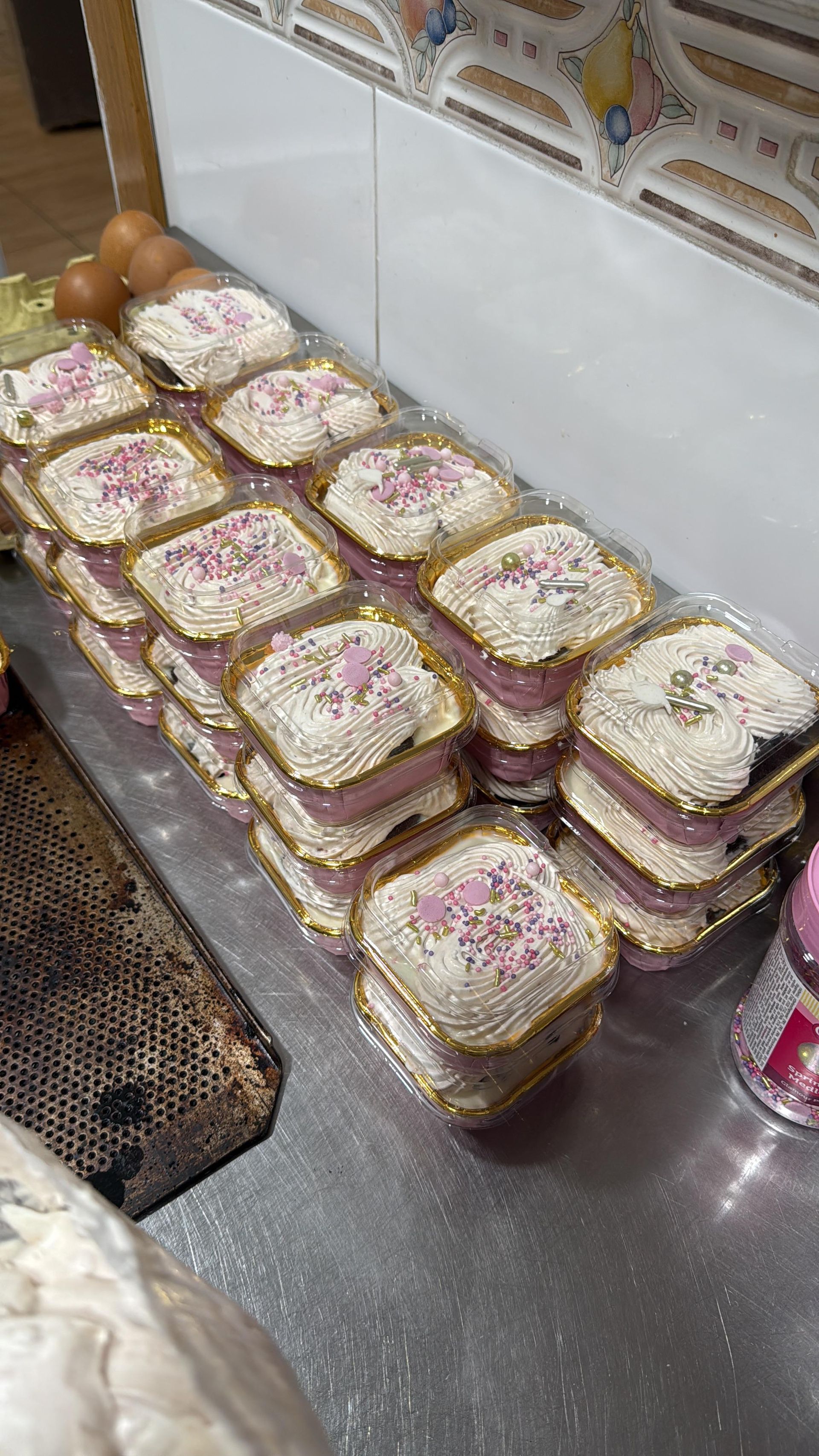 Pila de pasteles cuadrados con glaseado rosa, chispas y bordes dorados.