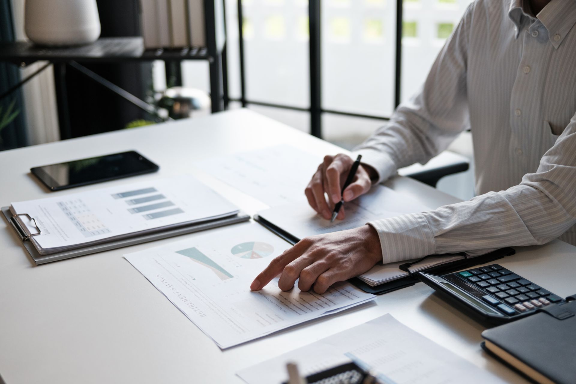 Une personne travaillant à un bureau, consultant des documents et utilisant une calculatrice.