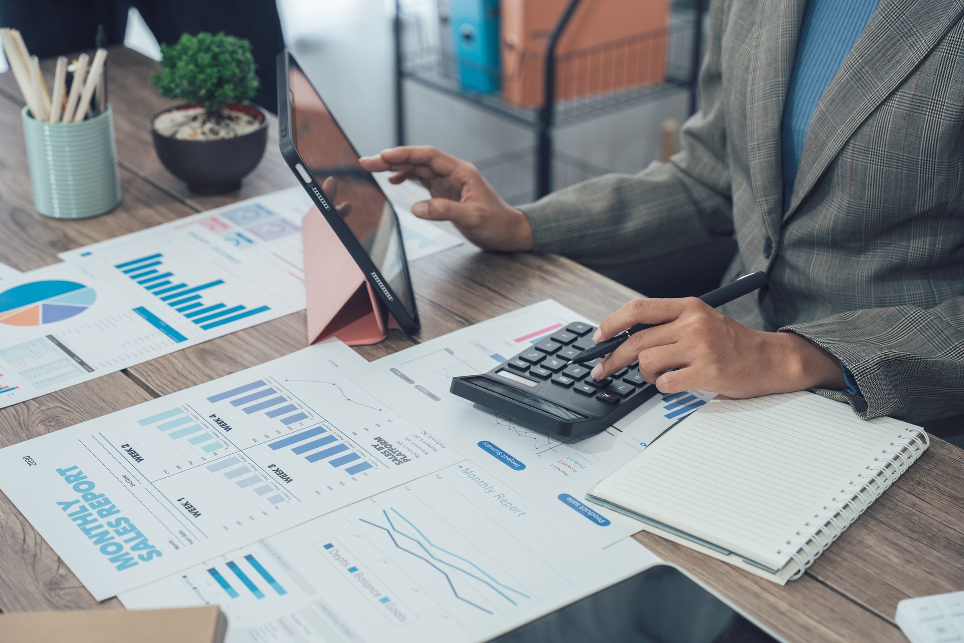 Trois personnes collaborent autour d'un ordinateur portable et de documents, assises à une table dans un bureau lumineux.