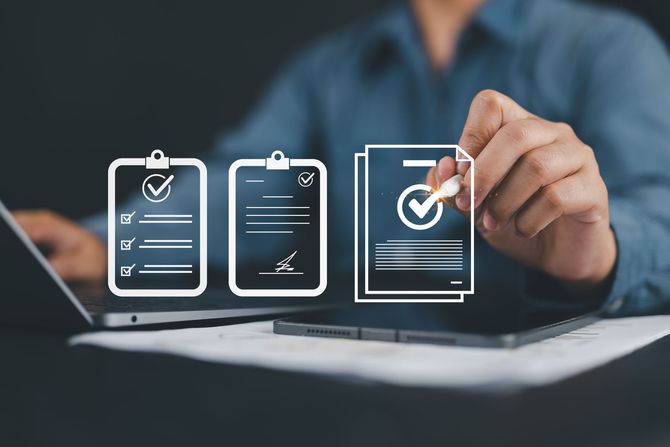 Personne examinant et approuvant des documents, utilisant un ordinateur portable et une tablette, avec des icônes 