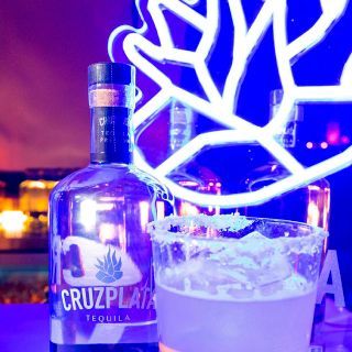 Una botella de tequila cruzplata junto a un vaso