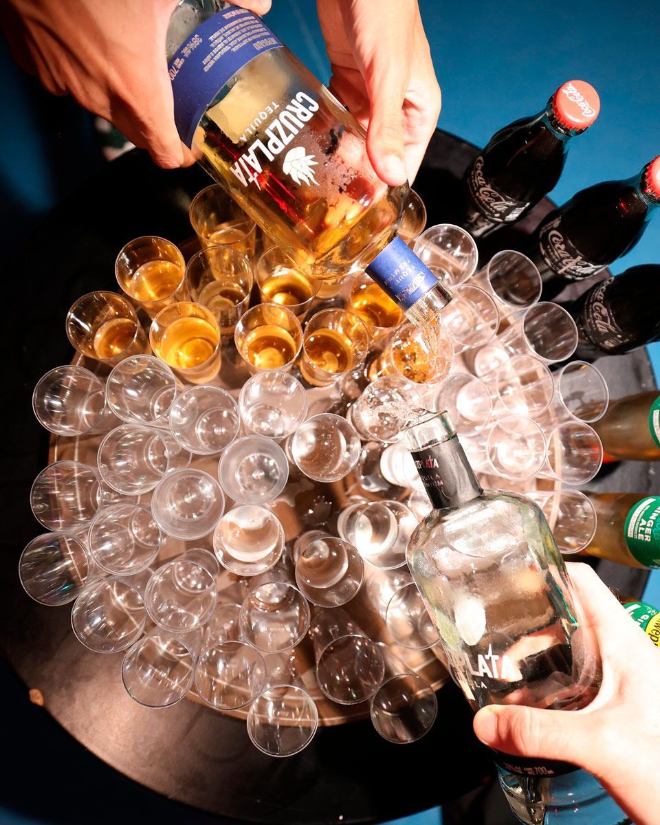 Se vierte una botella de Cruz Laza en un cubo de vasos de chupito.