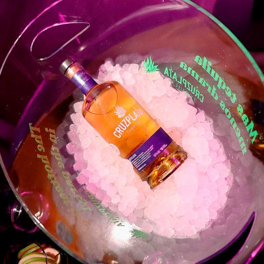 Una botella de Cruzplay reposa en un cubo de hielo.