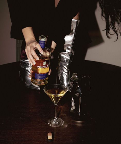 Una mujer está sirviendo una botella de Crown Royal en una copa de martini.