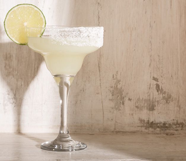 Una margarita con una rodaja de lima sobre una mesa de madera.