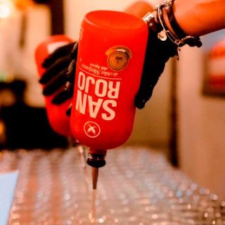 Se vierte una botella de San Rojo en un vaso.