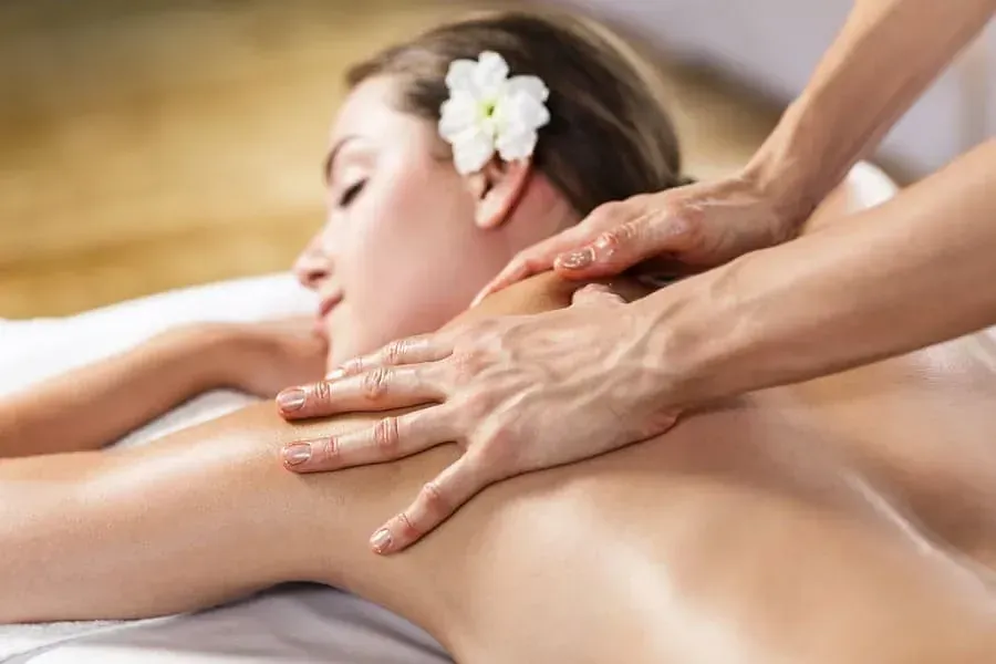 Una mujer está recibiendo un masaje en un spa con una flor en el pelo.