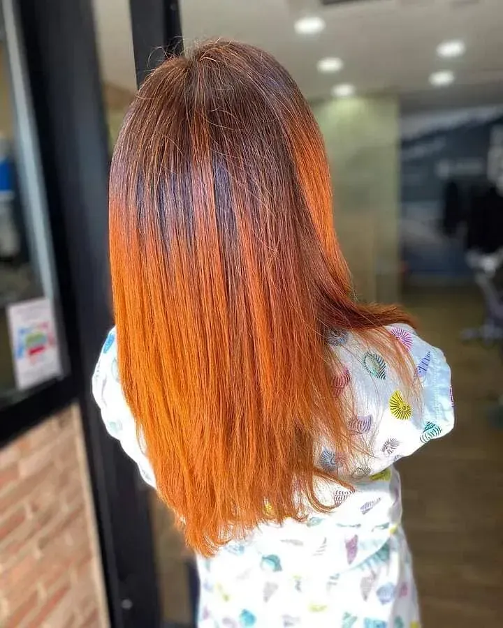 Una mujer con cabello largo y rojo está parada frente a una puerta.