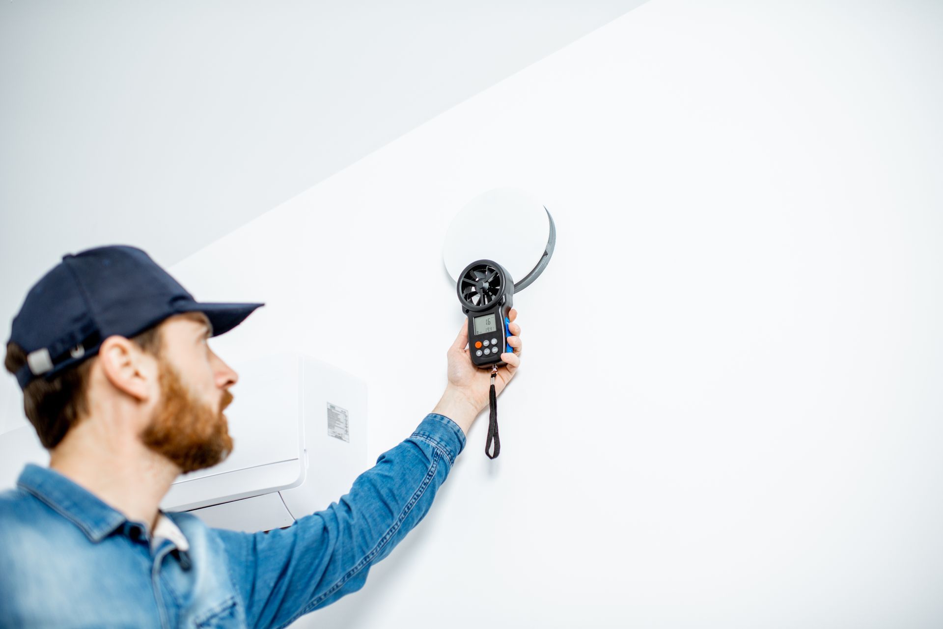 Un technicien testant la vitesse de ventilation dans une maison.