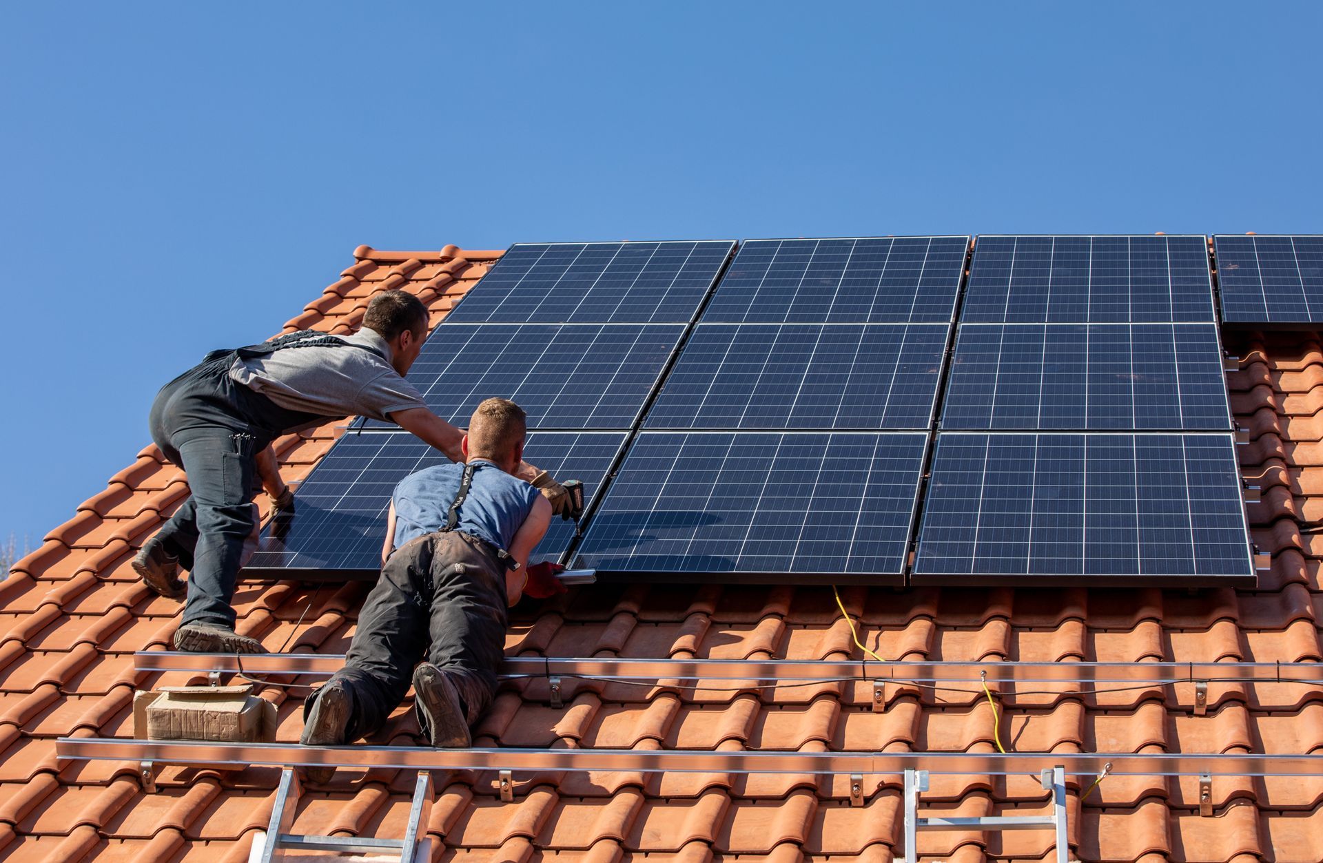 Deux techniciens professionnels intervenant sur des panneaux solaires installés sur une toiture.