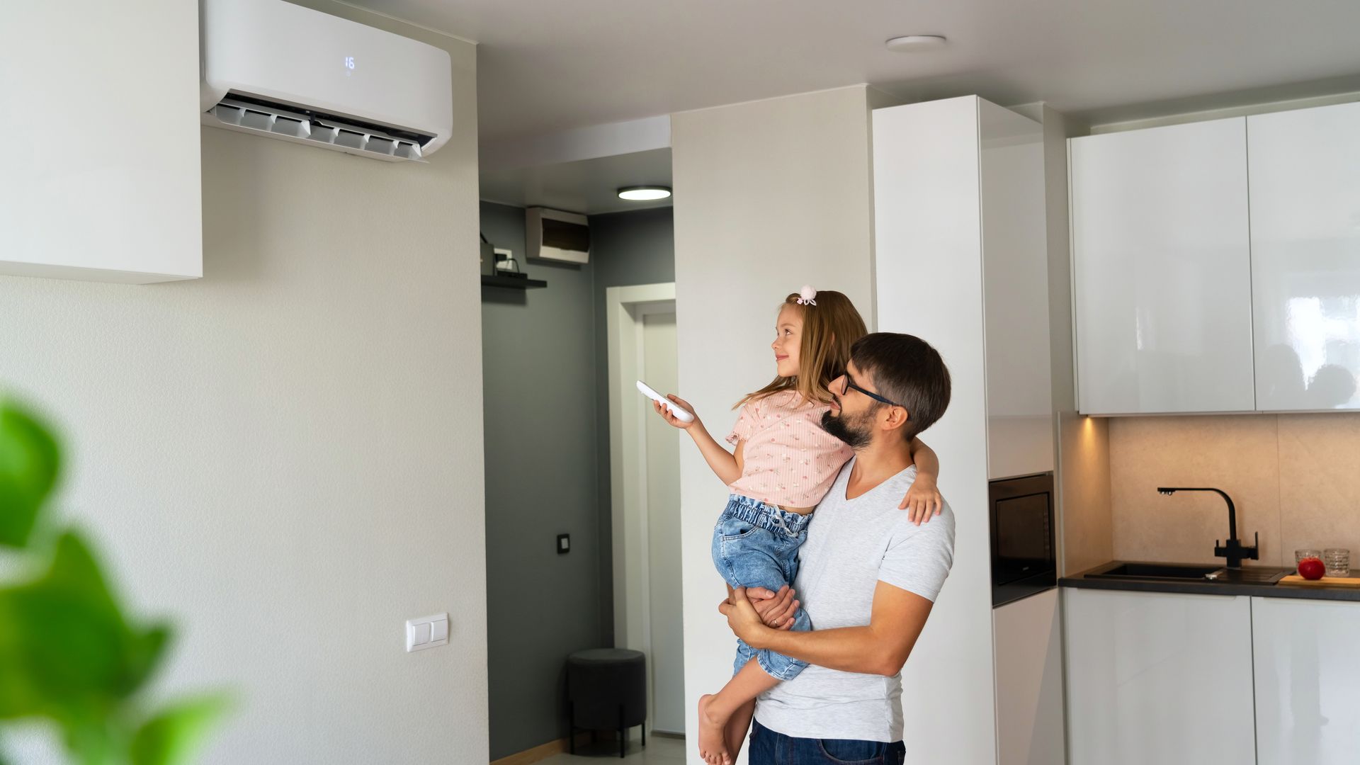 Un homme et sa fille contrôlant un climatiseur.