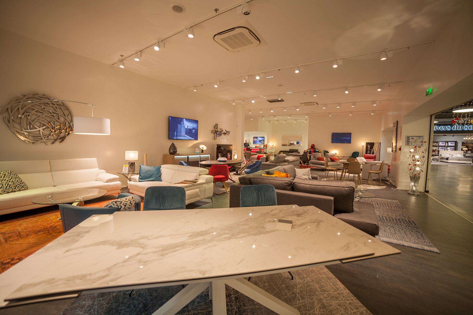 Table de repas effet marbre blanc réfléchissant les spots de lumière au plafond