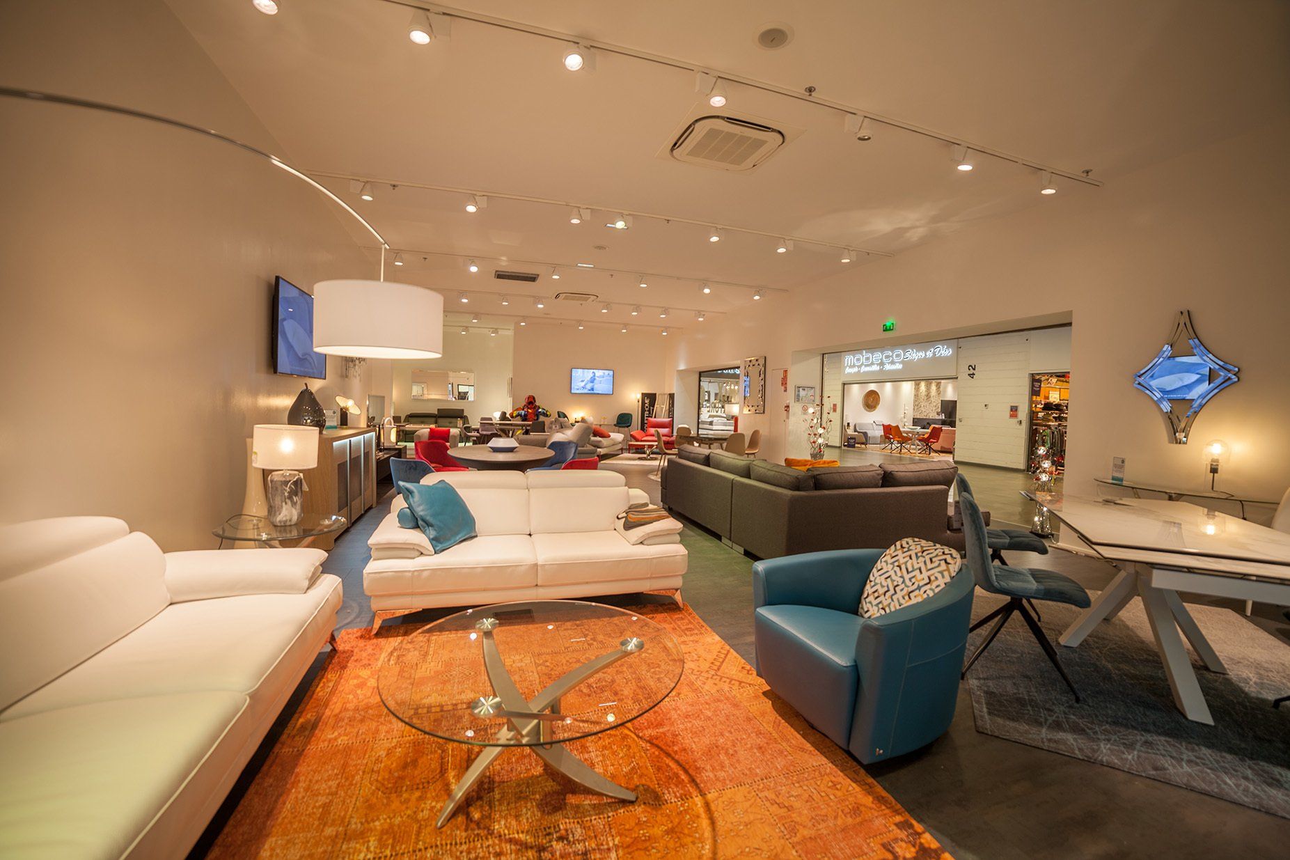 Photo panoramique du magasin home center avec un salon avec canapés, table basse et fauteuil