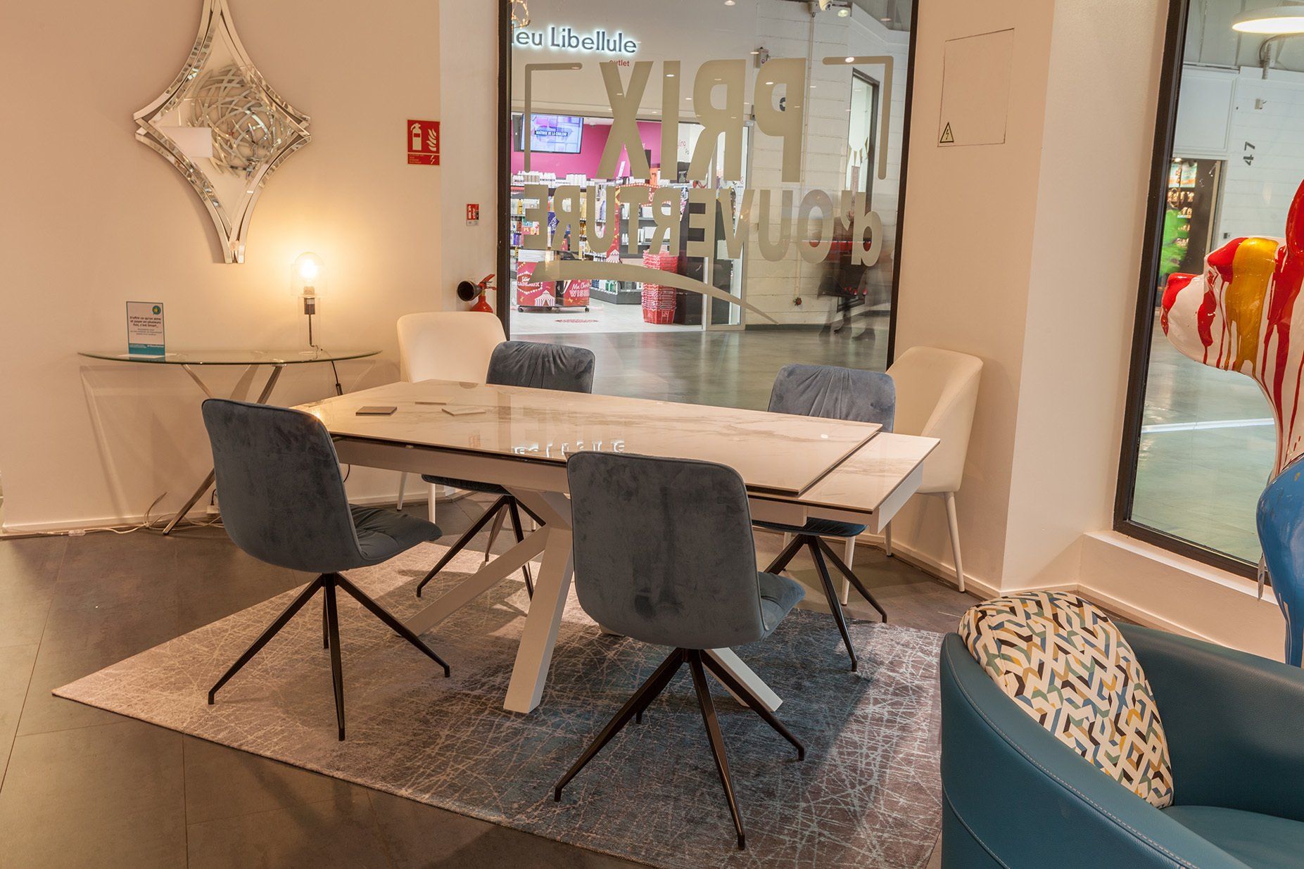 Table en céramique effet marbre extensible entourée de chaises en tissu bleu