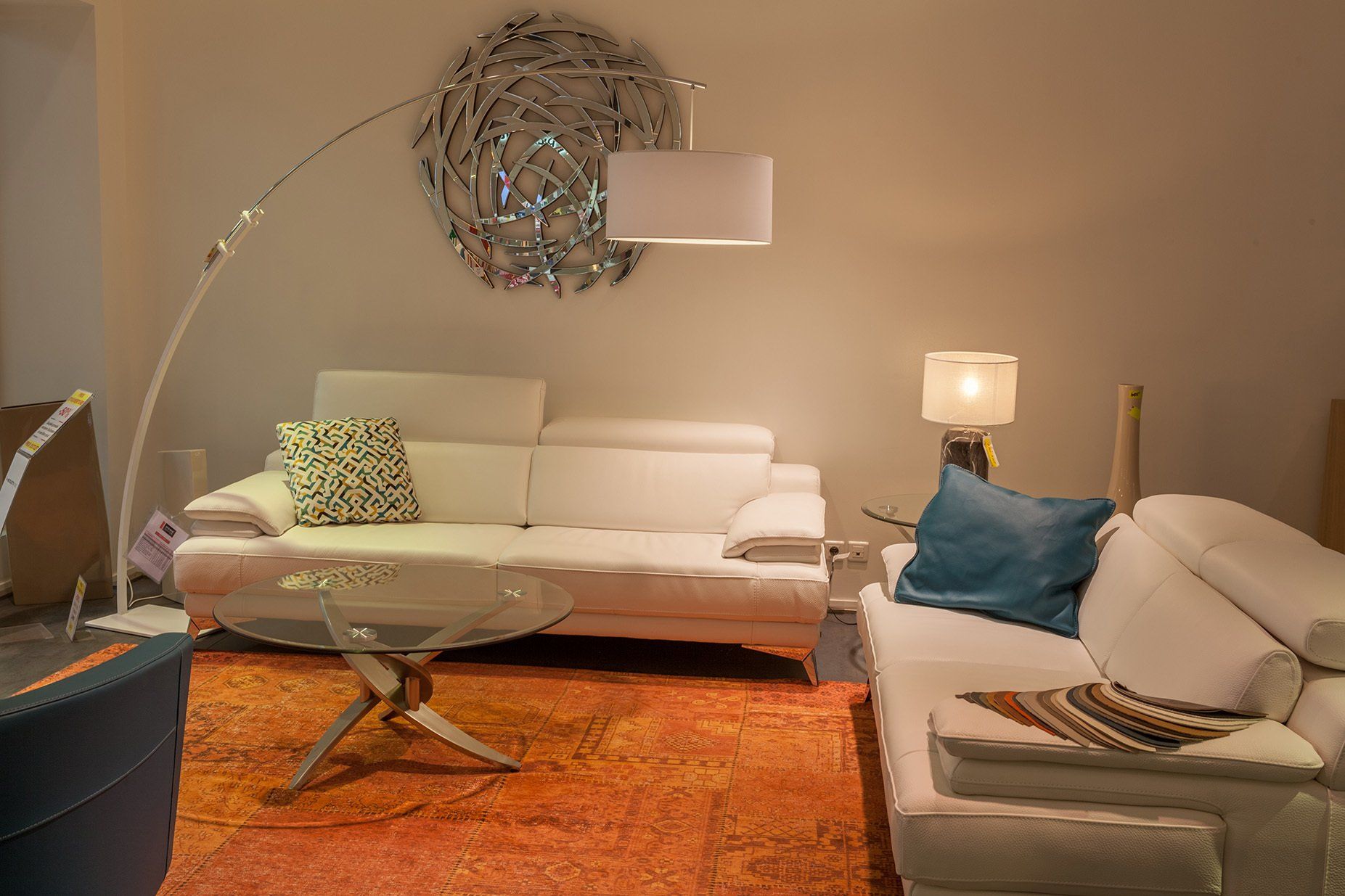 Deux canapés en cuir blanc devant table basse ronde en verre et tapis orange