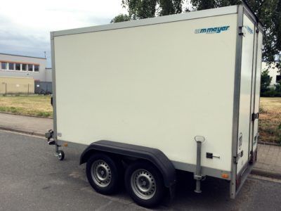 Ein weißer Anhänger steht am Straßenrand.