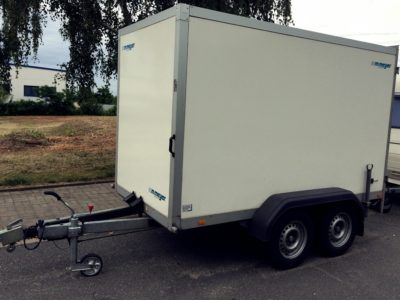 Ein weißer Anhänger steht am Straßenrand.