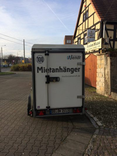 Ein weißer Anhänger steht am Straßenrand.