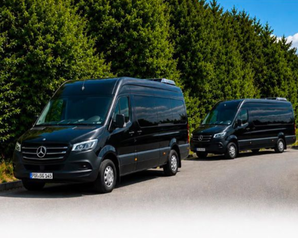 Zwei schwarze Mercedes-Transporter stehen nebeneinander auf einer Kopfsteinpflasterstraße.