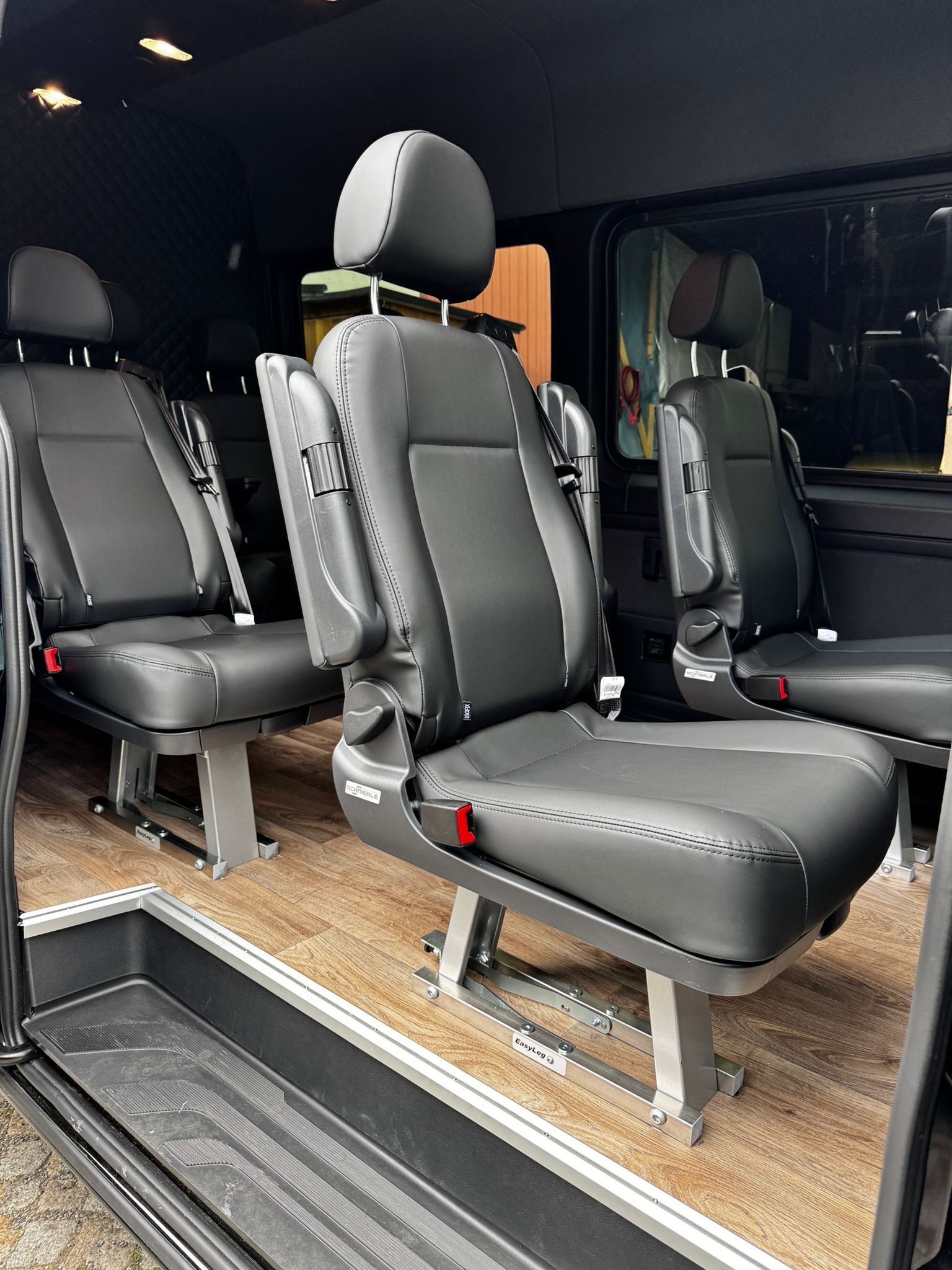 Eine Reihe schwarzer Ledersitze in einem Lieferwagen.