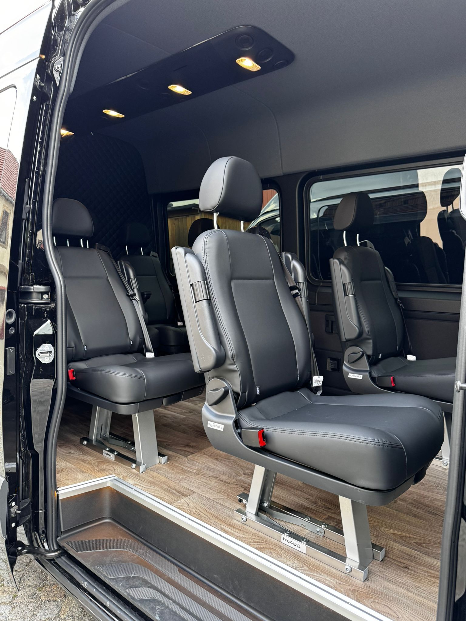 Das Innere eines schwarzen Lieferwagens mit vielen Sitzen.