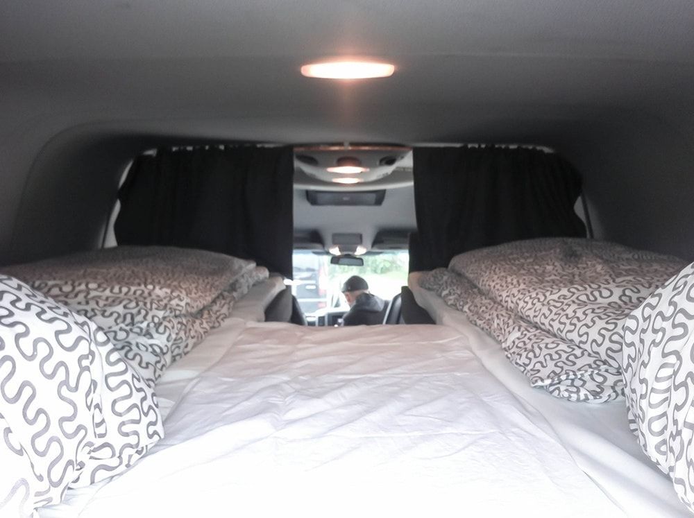 Ein Bett im hinteren Teil eines Lieferwagens mit einer Bettdecke mit Leopardenmuster