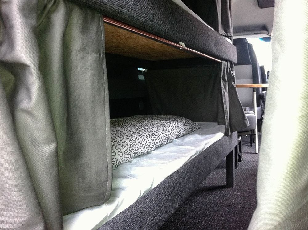 Ein Etagenbett mit Vorhängen im hinteren Teil eines Lieferwagens.