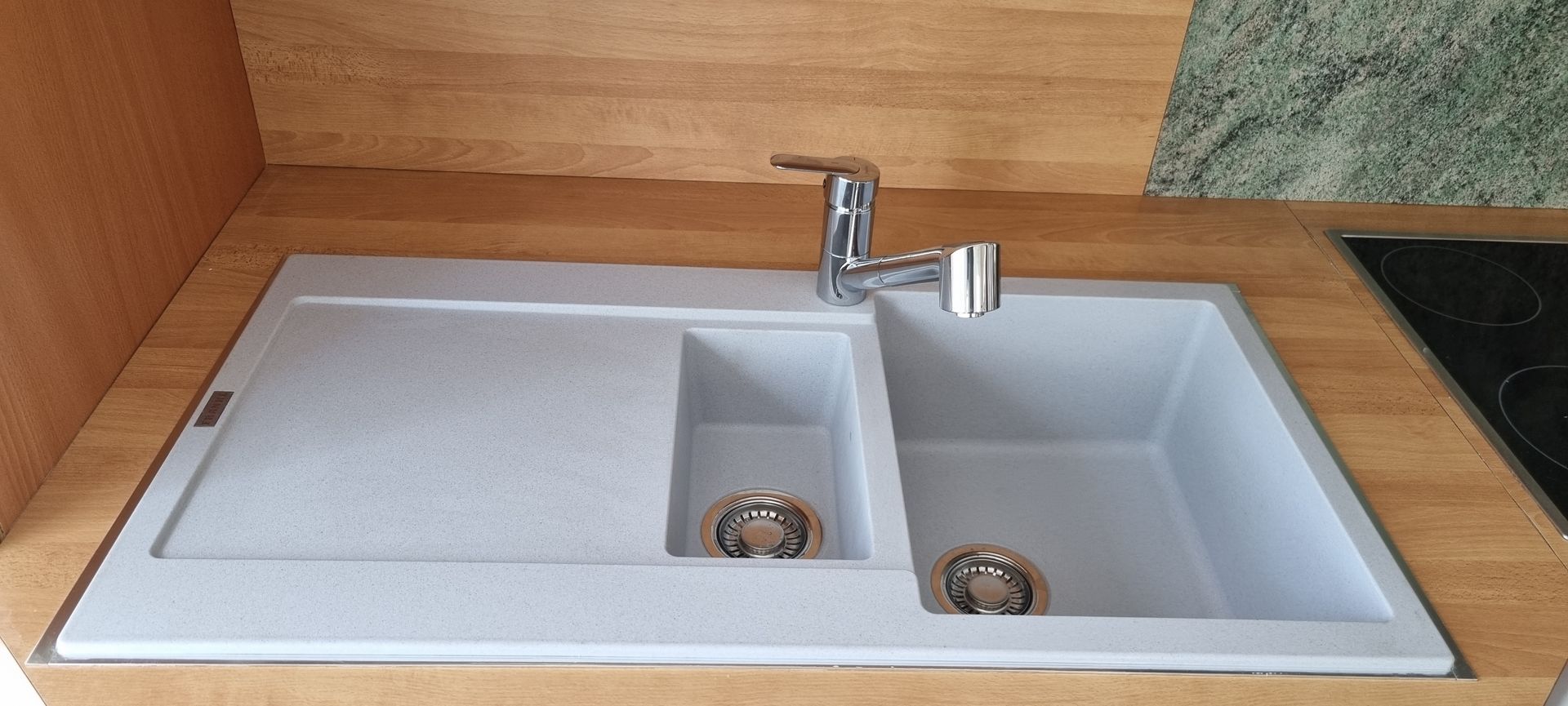 Évier de cuisine à deux bacs et robinet, encastré dans un plan de travail en bois.