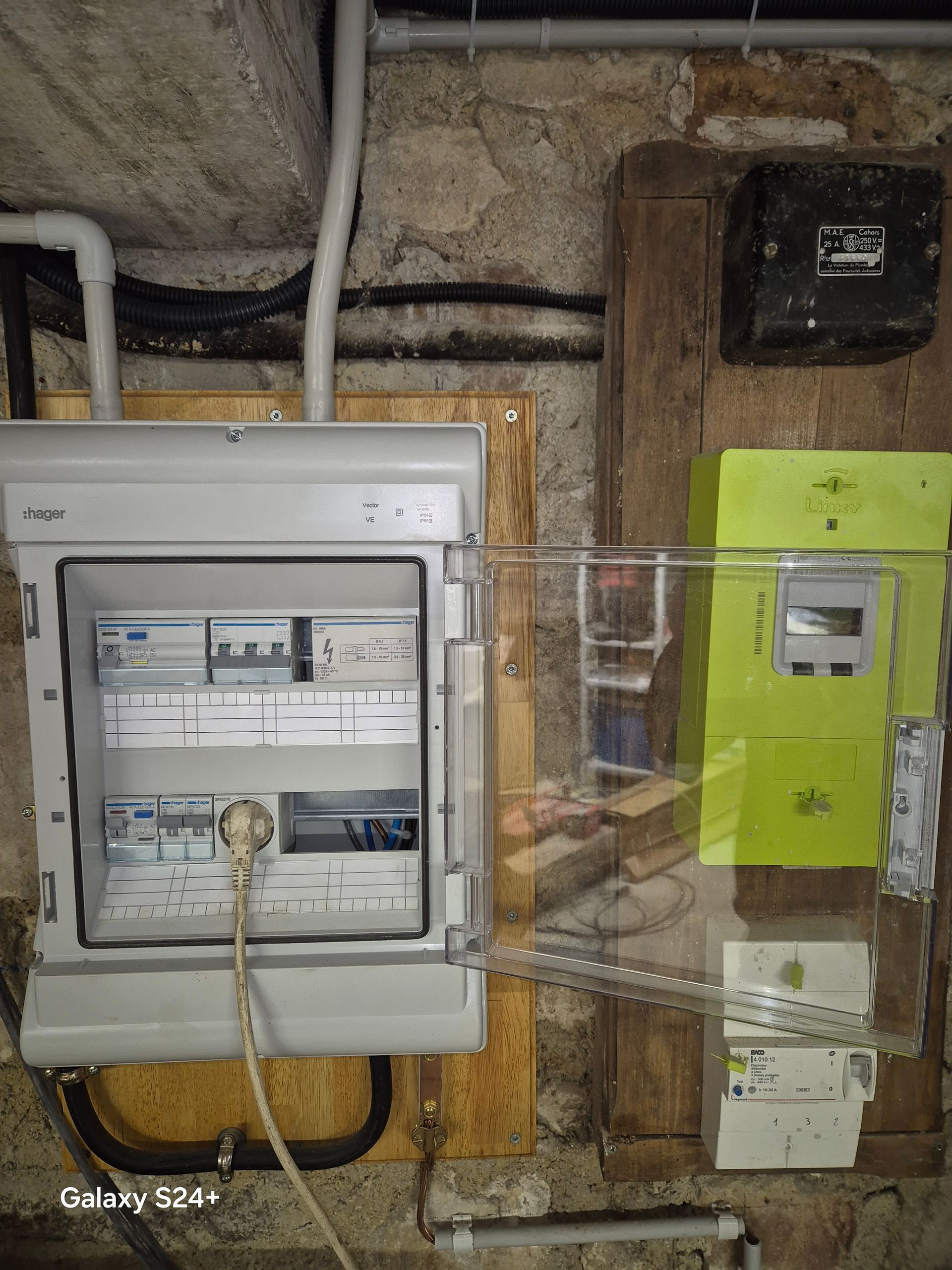 Tableau électrique mural avec disjoncteurs et compteur. Tons gris, verts et bruns.