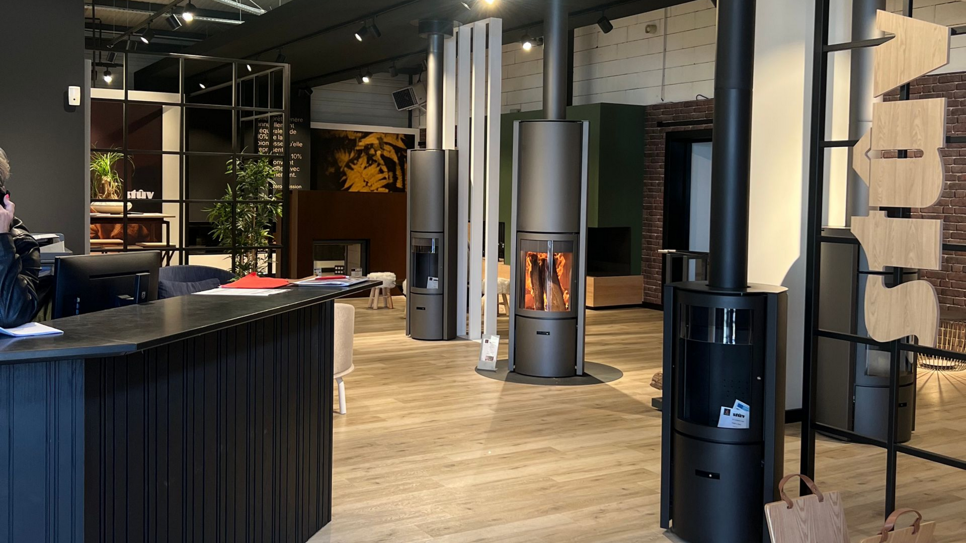 Salle d'exposition avec plusieurs cheminées modernes et un comptoir d'accueil.