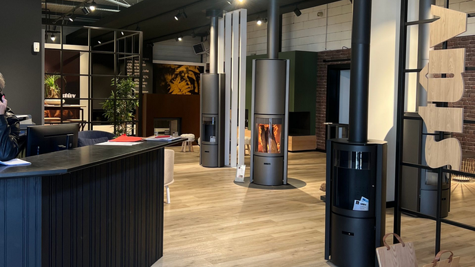 Salle d'exposition avec plusieurs cheminées modernes et un comptoir d'accueil.