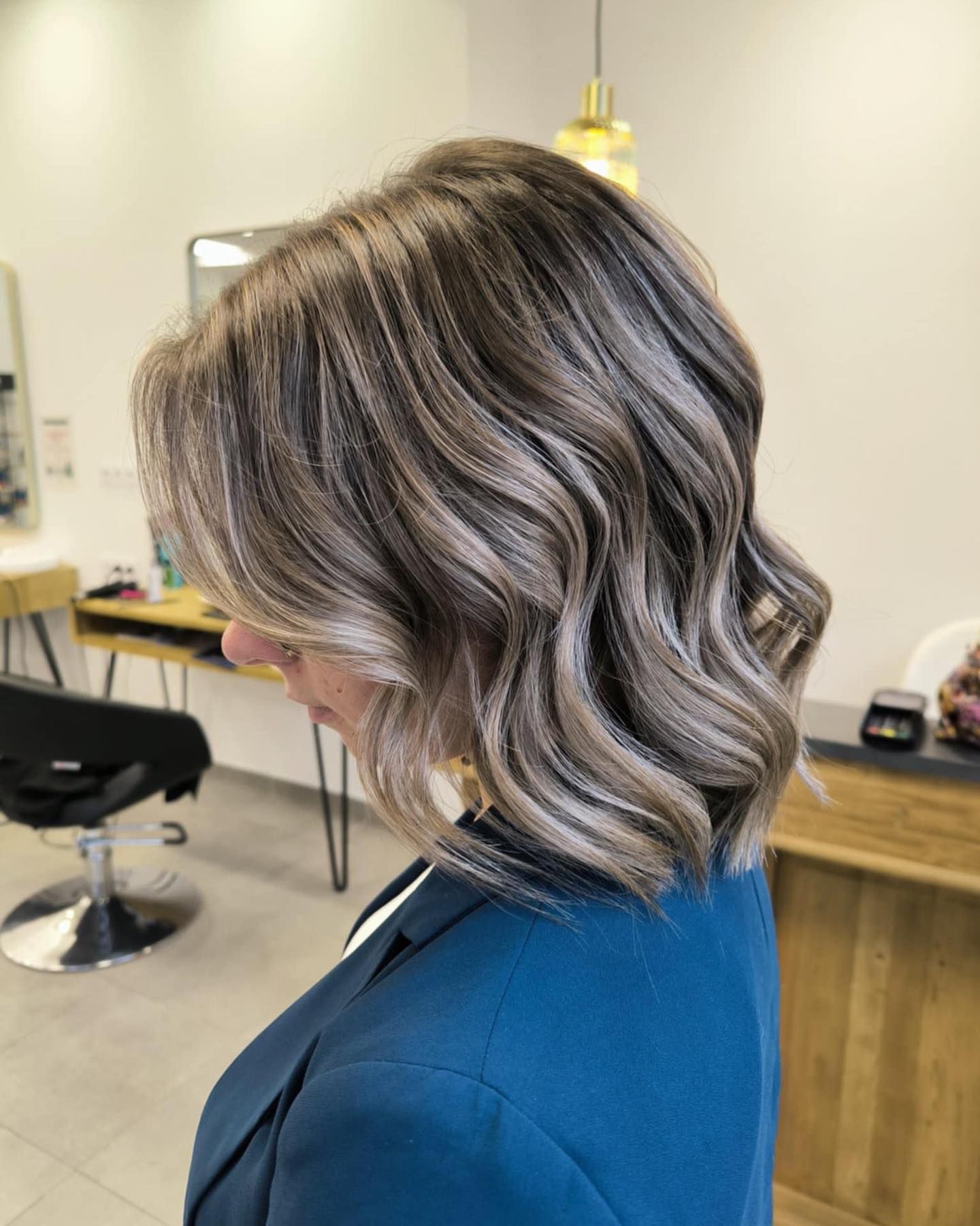 Femme aux cheveux ondulés et méchés ; dans un salon de coiffure.