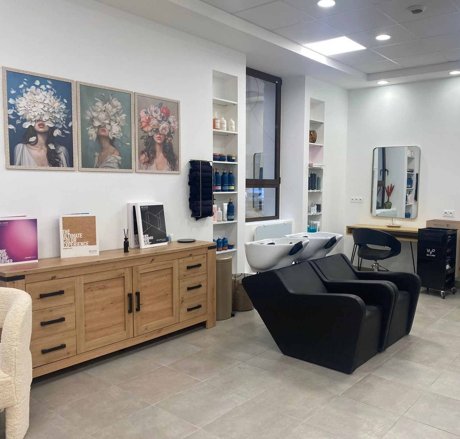 Intérieur d'un salon de coiffure avec postes de coiffage, lavabos et décorations murales.