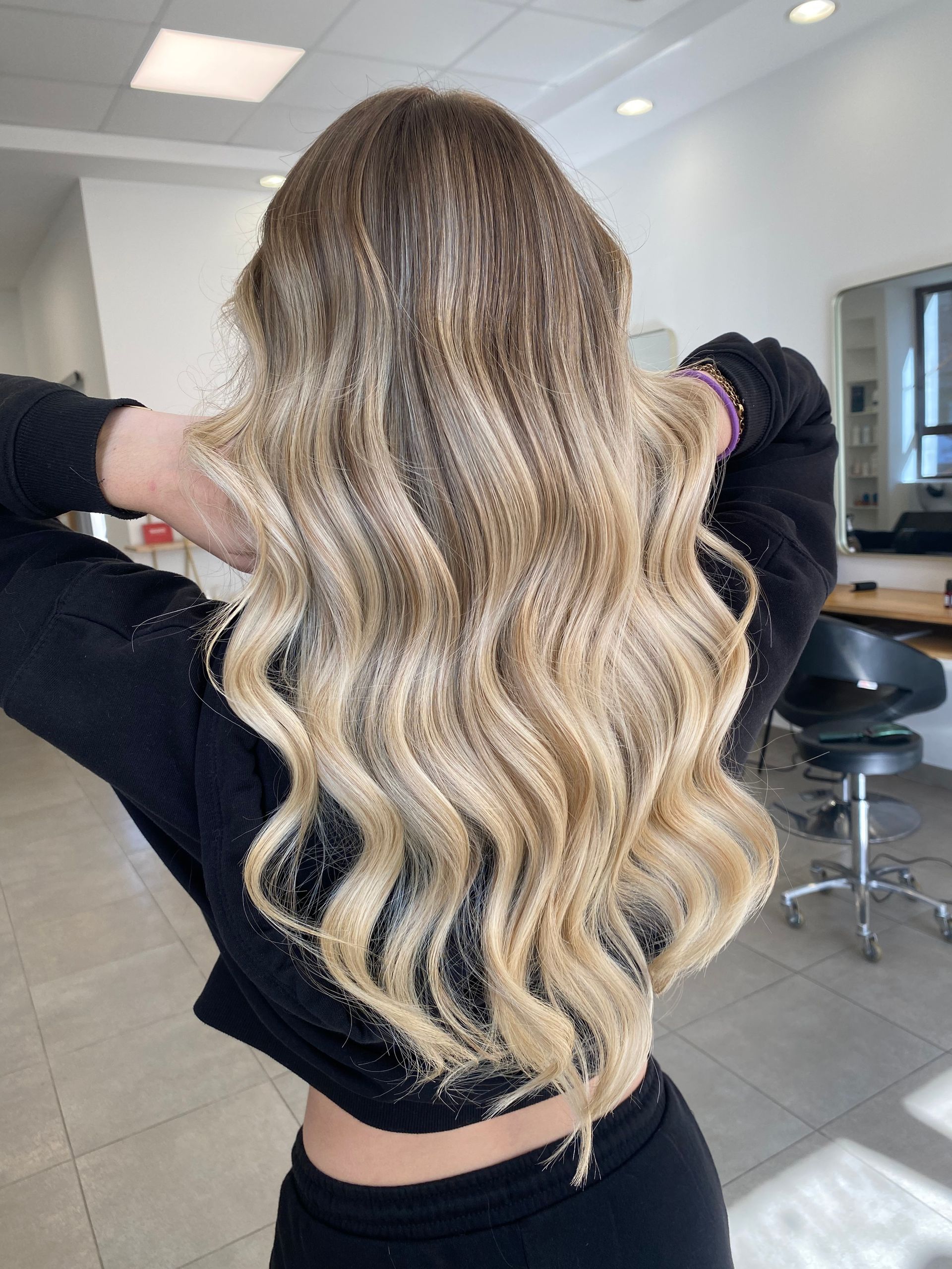 Intérieur d'un salon de coiffure avec postes de coiffage, lavabos et décorations murales.