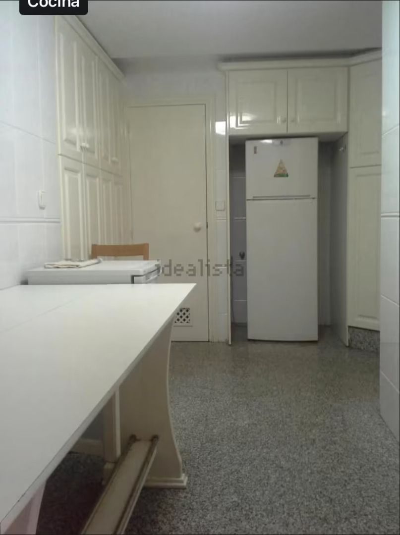 Una cocina con gabinetes blancos y un refrigerador blanco.