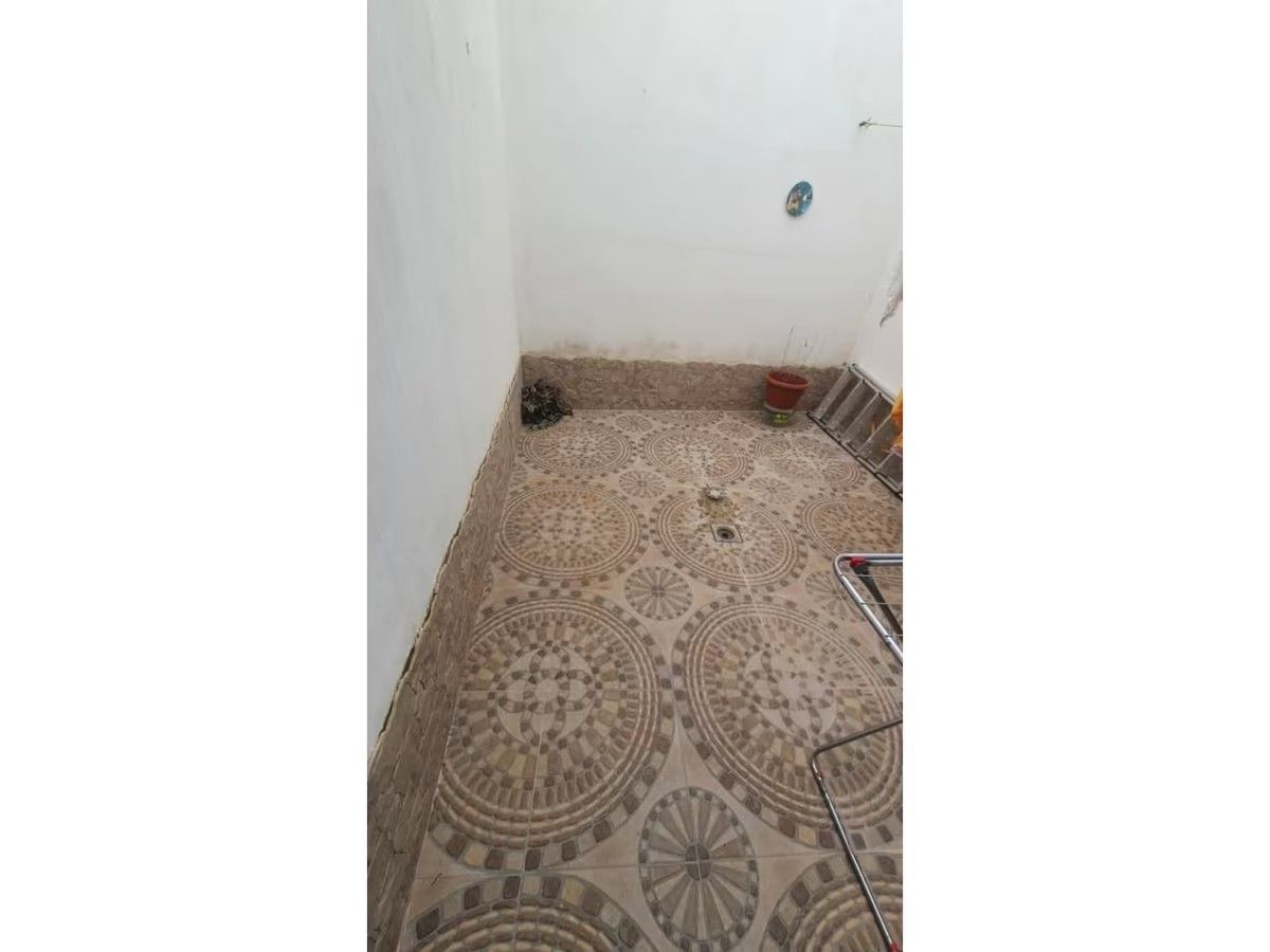 Un baño con suelo de baldosas y pared blanca.