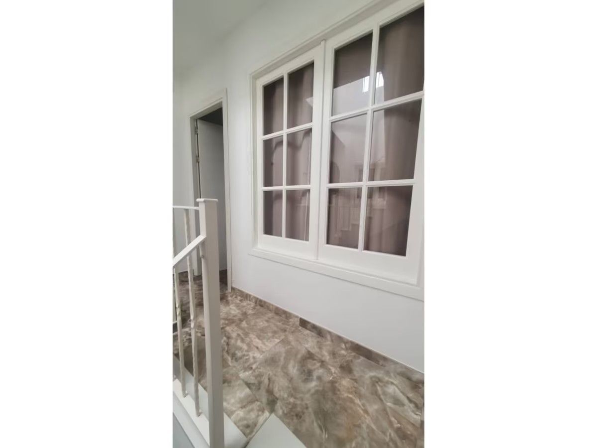 Un pasillo con escaleras y dos ventanas en la pared.