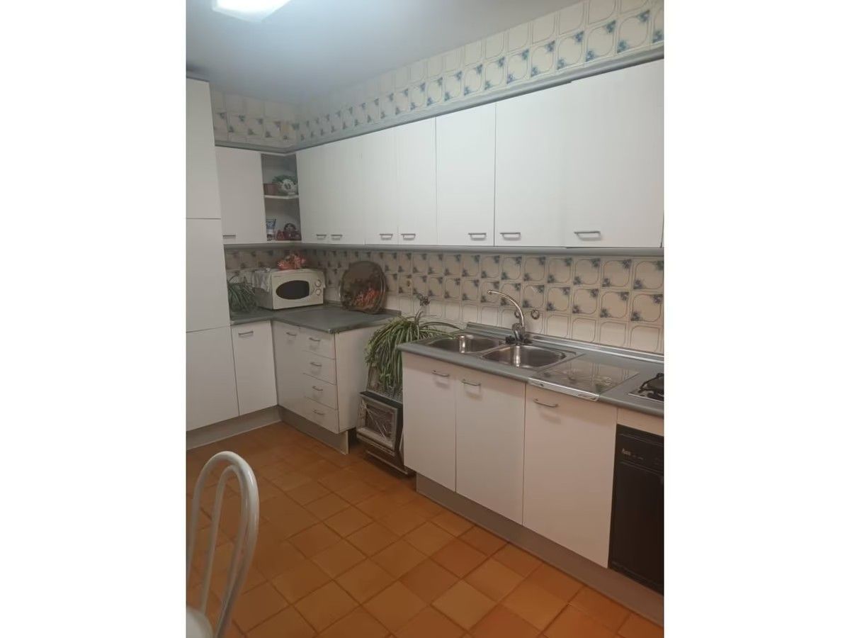 Una cocina con gabinetes blancos y electrodomésticos de acero inoxidable.