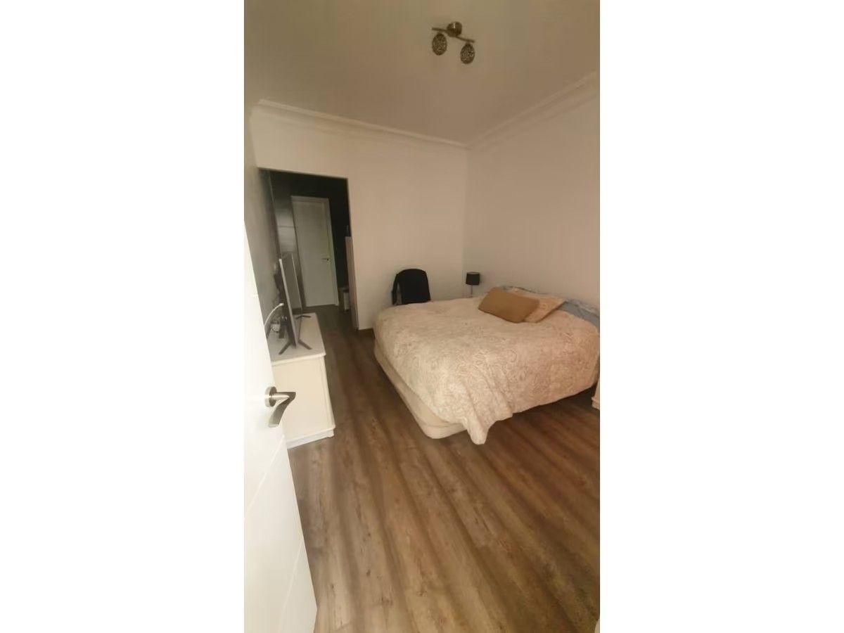 Un dormitorio con cama, televisión y suelo de madera.