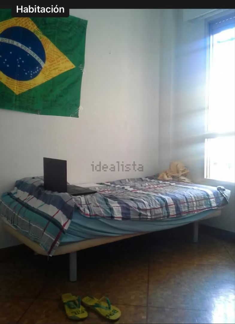 Un dormitorio con una cama y una computadora portátil encima.