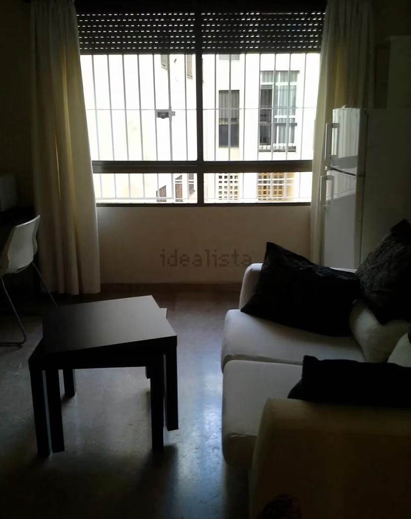 Una sala de estar con un sofá, una mesa y una ventana.