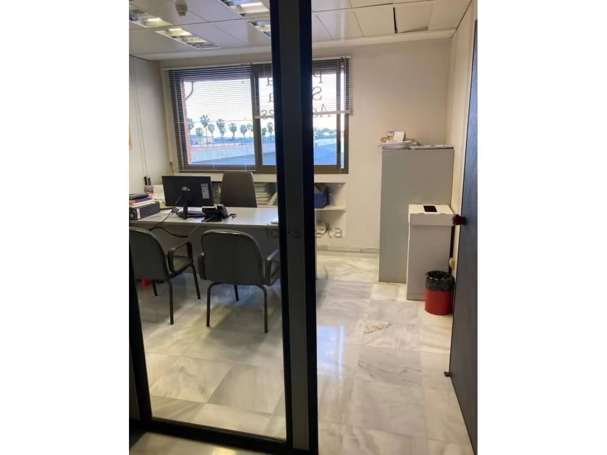 Una habitación con un escritorio y sillas y una puerta de vidrio.