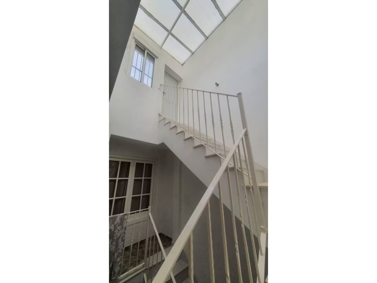 Una escalera con barandilla y una claraboya encima.