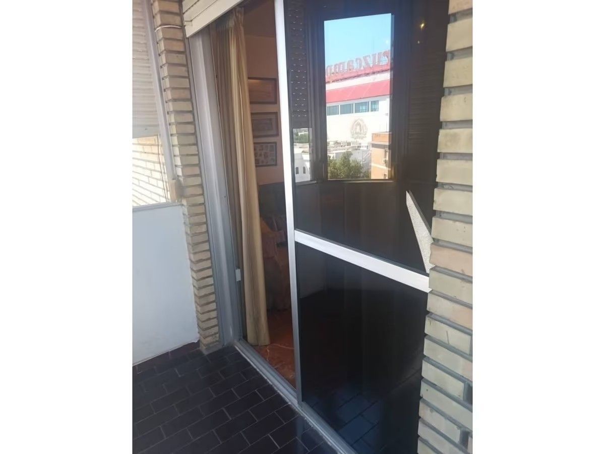 Una puerta negra con un espejo se abre a un balcón.