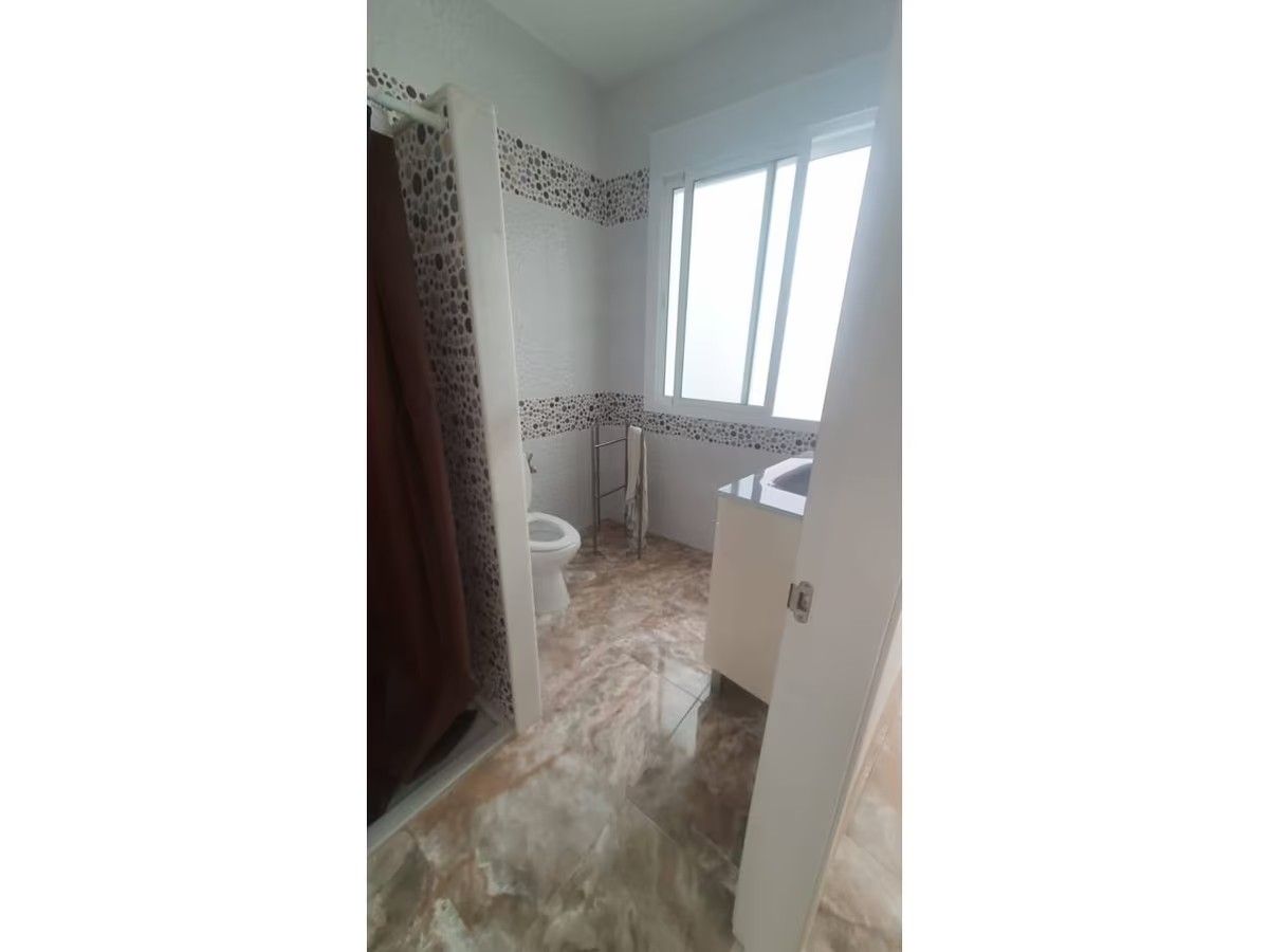 Un baño con inodoro, lavabo y ventana.