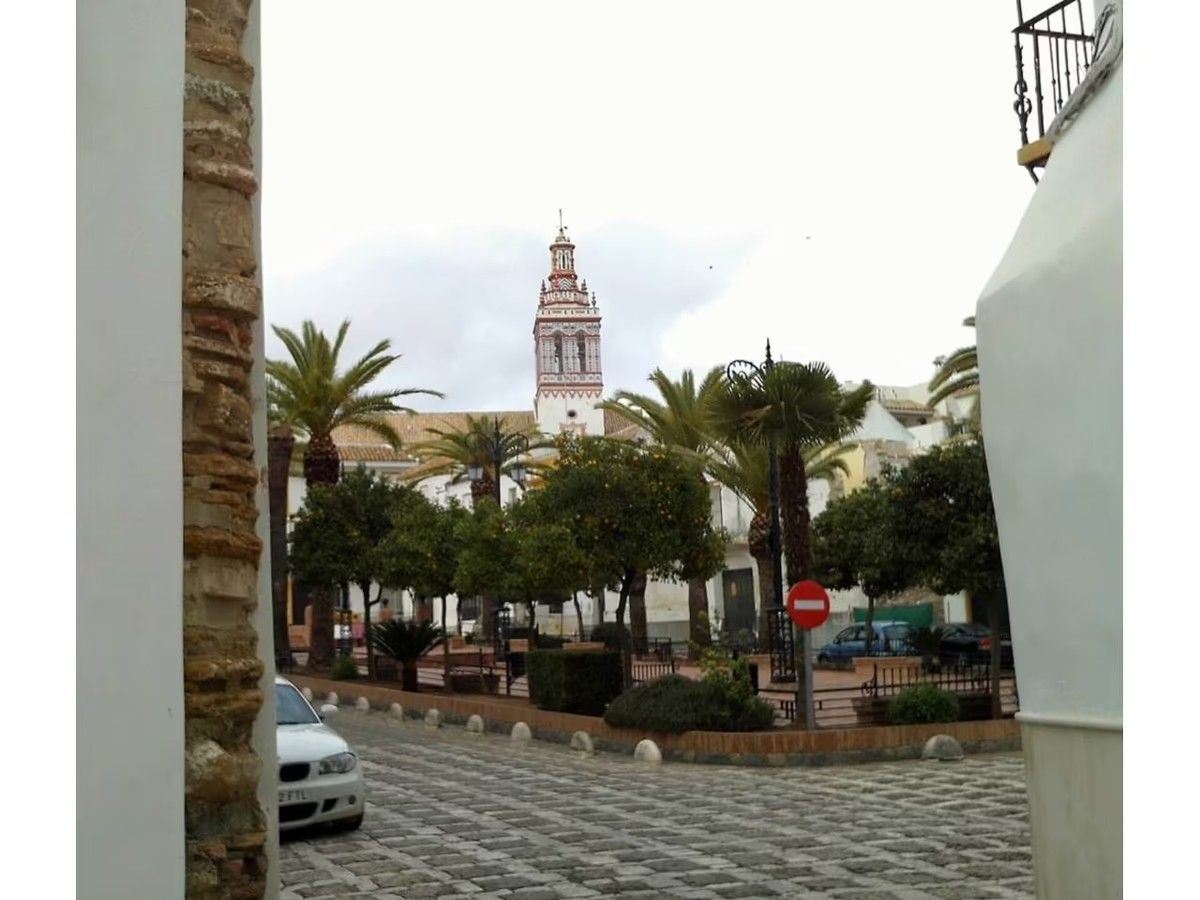 Un coche blanco está aparcado delante de una torre de reloj.