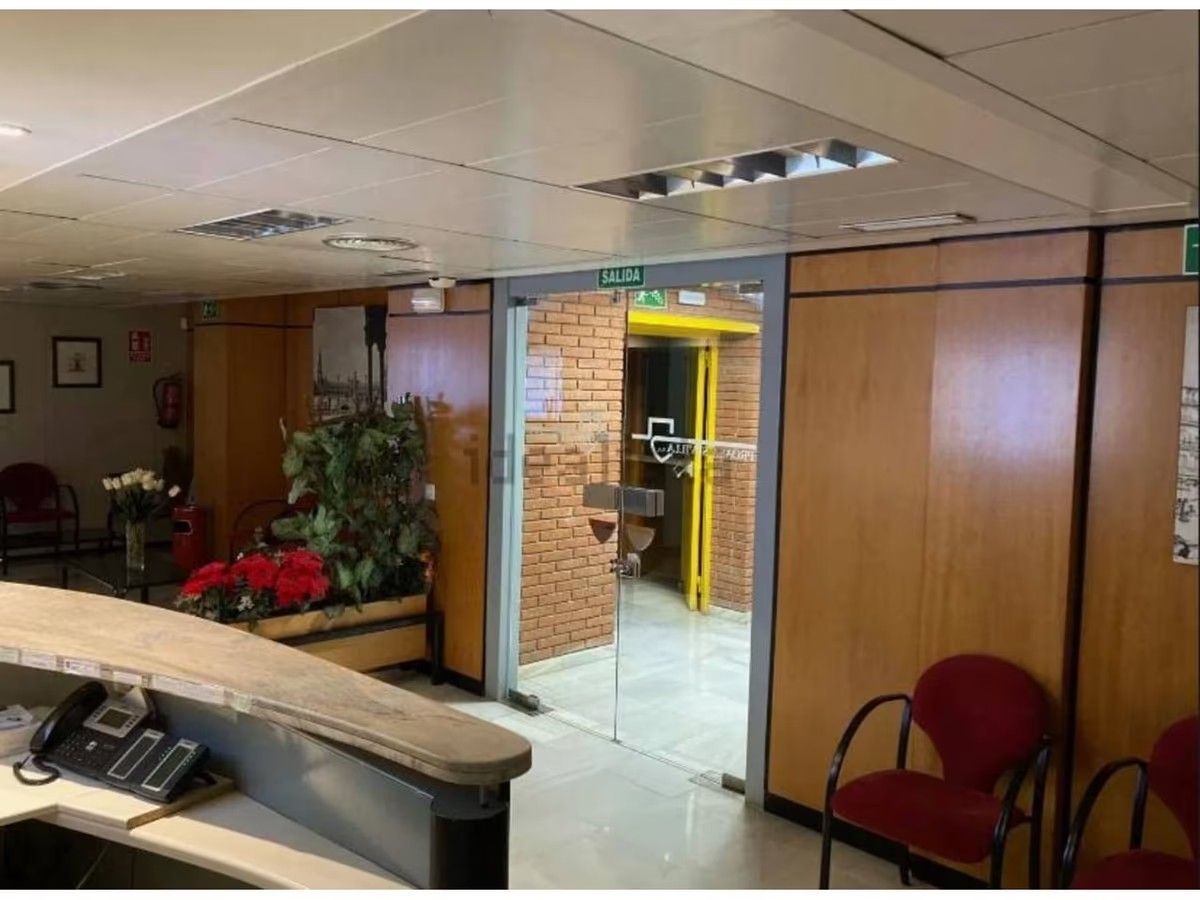 Una sala de espera con sillas rojas y una puerta de cristal.