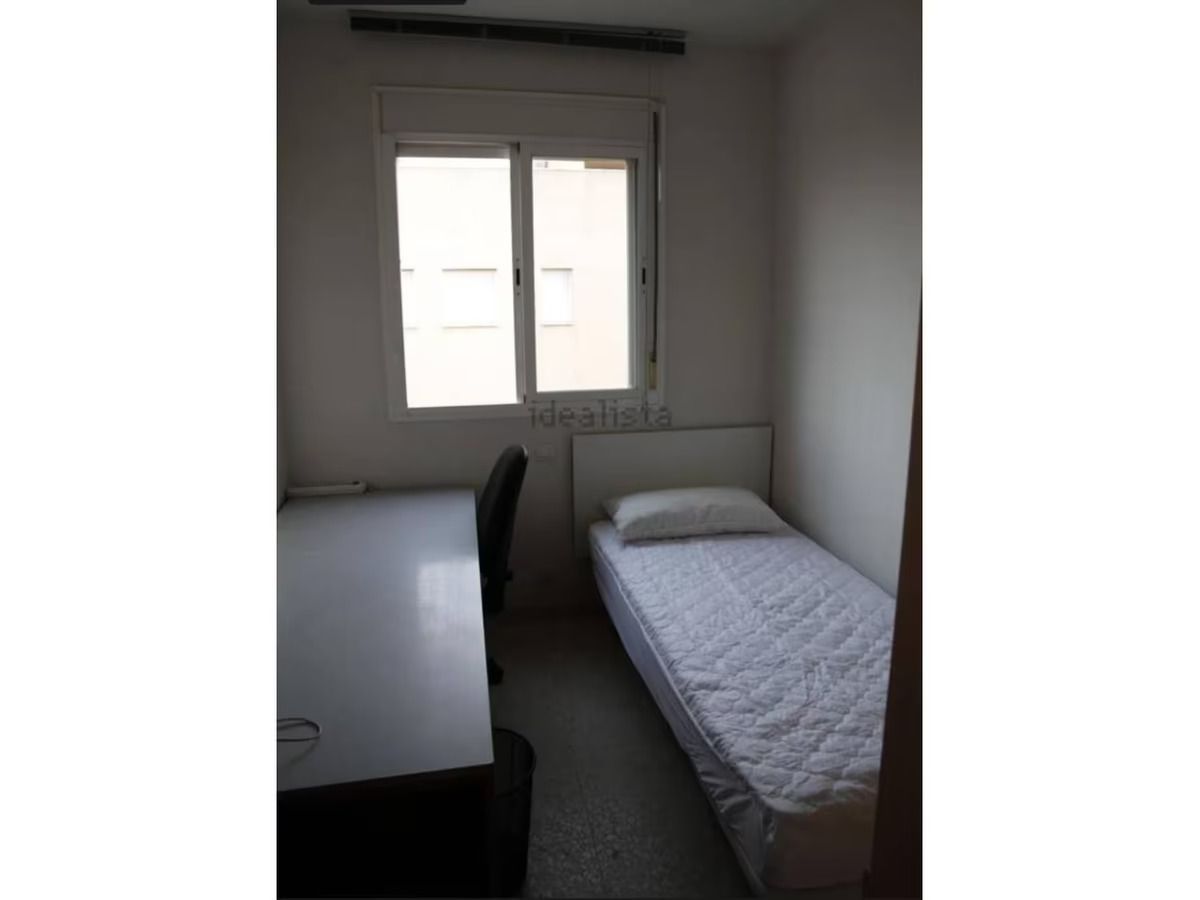 Un dormitorio con una cama individual, escritorio y ventana.