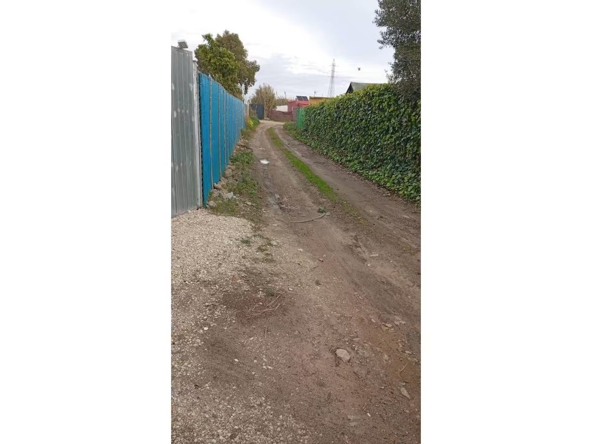 Un camino de tierra con una valla azul al costado.