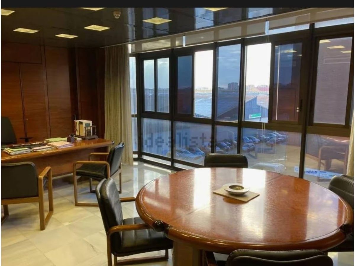 Una sala de conferencias con una mesa redonda y sillas frente a un gran ventanal.